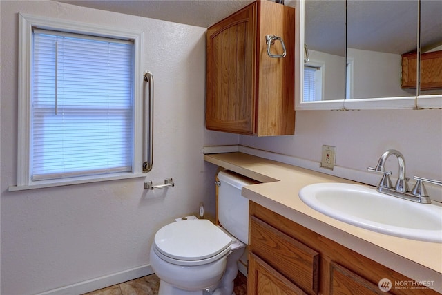 half bath with vanity, toilet, and baseboards