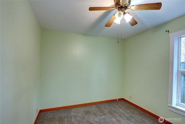 unfurnished room with a ceiling fan, baseboards, and dark carpet