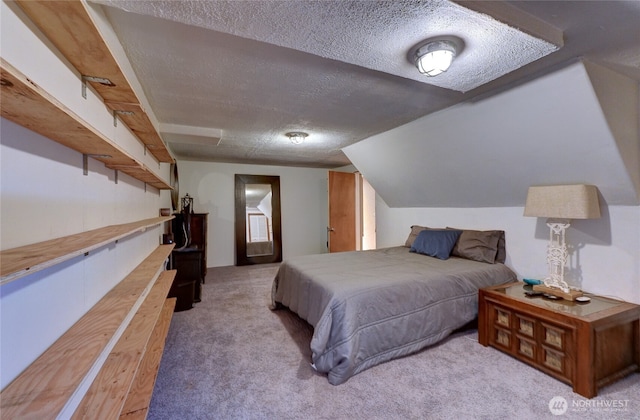 bedroom with vaulted ceiling, carpet floors, and a textured ceiling