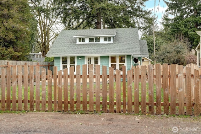 view of front of property featuring a fenced front yard and a shingled roof