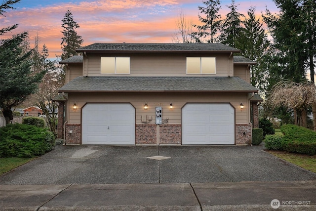 view of front facade featuring driveway, brick siding, an attached garage, and a shingled roof