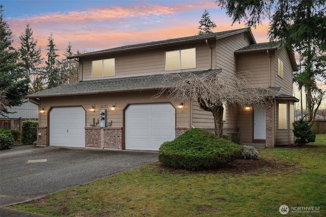 view of front of home with driveway, an attached garage, a lawn, and brick siding