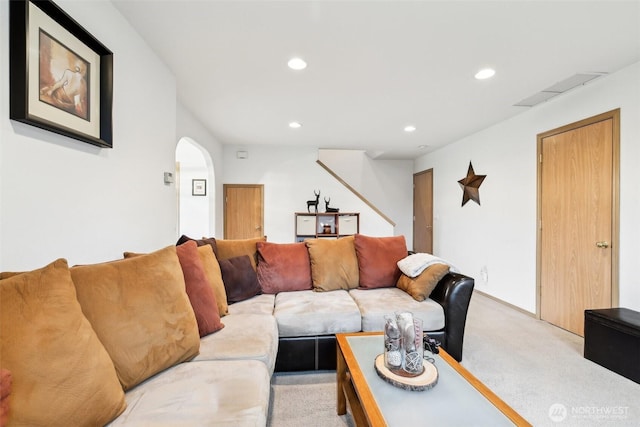 living area featuring light carpet, arched walkways, visible vents, and recessed lighting