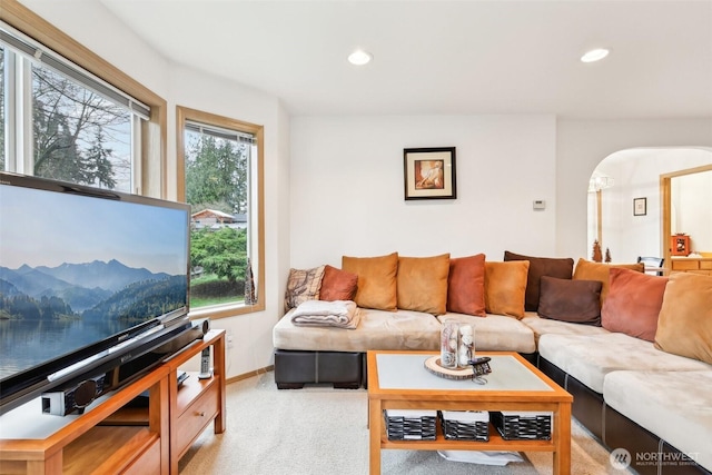 living room with arched walkways, recessed lighting, baseboards, and light colored carpet