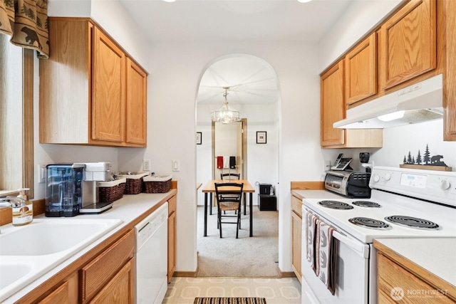 kitchen featuring under cabinet range hood, white appliances, and light countertops