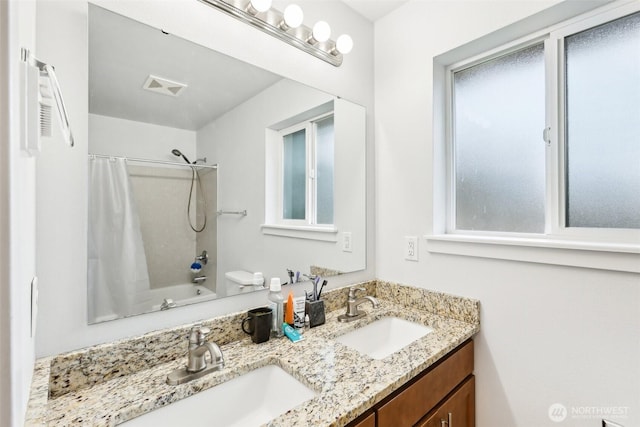 bathroom featuring visible vents, double vanity, a sink, and shower / bath combo with shower curtain