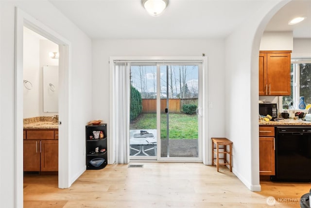 doorway to outside featuring light wood-style floors, arched walkways, visible vents, and baseboards