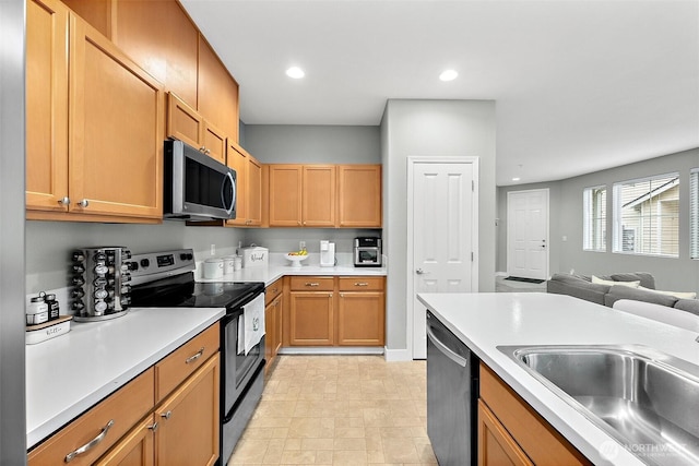 kitchen featuring recessed lighting, a sink, open floor plan, light countertops, and appliances with stainless steel finishes