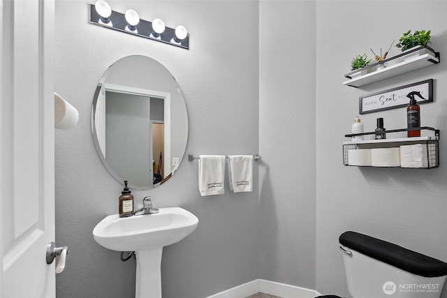 half bathroom featuring baseboards and toilet