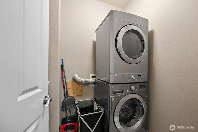 laundry area featuring laundry area, stacked washer / drying machine, and a textured wall