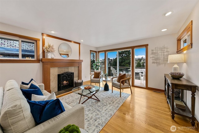 living area featuring light wood-style floors, a fireplace, baseboards, and recessed lighting