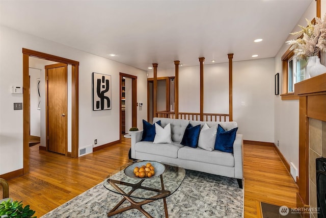 living area with baseboards, wood finished floors, visible vents, and recessed lighting