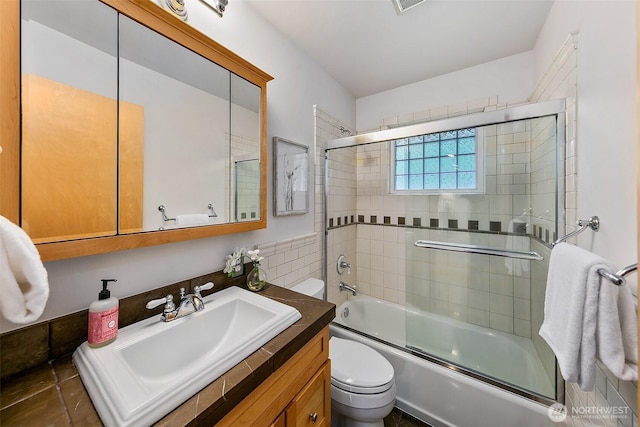 bathroom with visible vents, combined bath / shower with glass door, vanity, and toilet