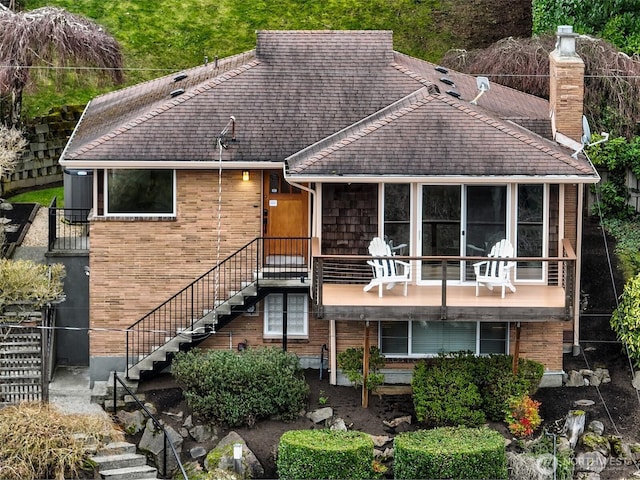 view of front facade featuring brick siding, stairway, and a chimney