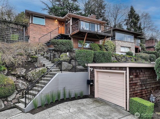 view of front of property with stairs, driveway, brick siding, and a garage