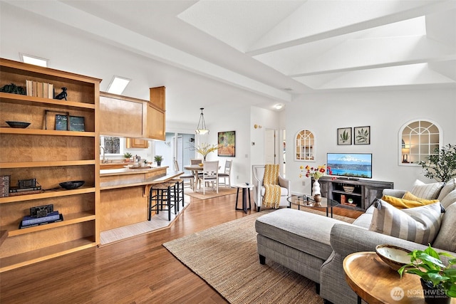 living area with lofted ceiling with beams and wood finished floors