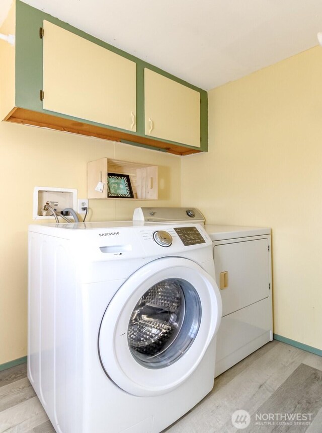 washroom featuring light wood-style floors, cabinet space, baseboards, and separate washer and dryer
