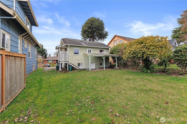 rear view of property featuring a lawn and fence