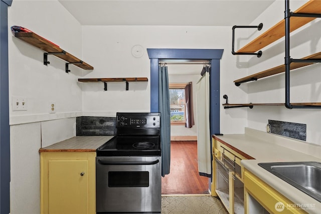 kitchen with open shelves, light wood finished floors, stainless steel electric range, and light countertops