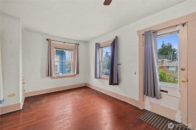 unfurnished room featuring visible vents, baseboards, a healthy amount of sunlight, and wood finished floors