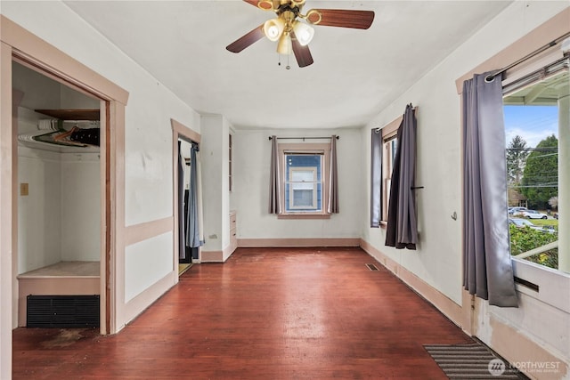 unfurnished room with visible vents, a healthy amount of sunlight, baseboards, and wood finished floors