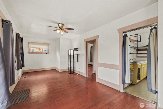 spare room featuring visible vents, a ceiling fan, a sink, wood finished floors, and baseboards