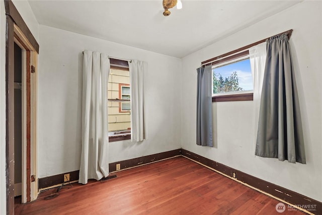 unfurnished room with baseboards and dark wood-type flooring