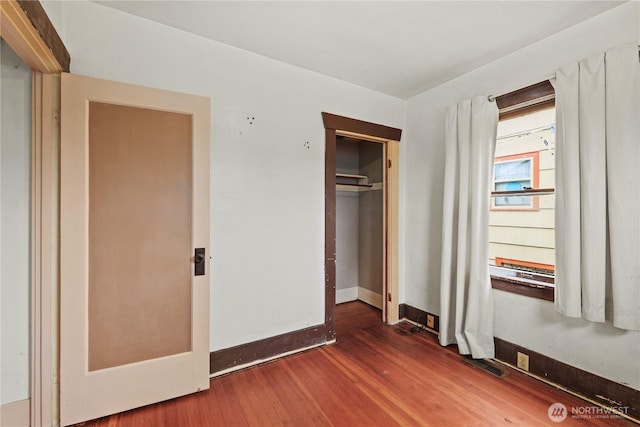 unfurnished bedroom featuring visible vents, wood finished floors, baseboards, and a closet