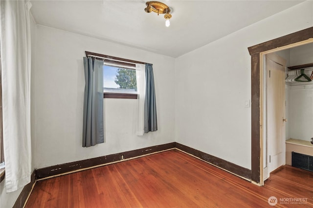 empty room with visible vents, baseboards, and wood finished floors