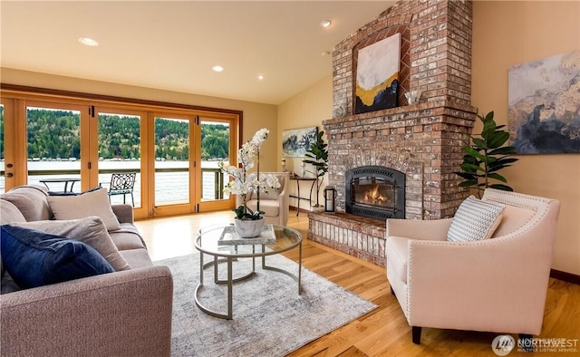 living area with a brick fireplace, vaulted ceiling, wood finished floors, and recessed lighting