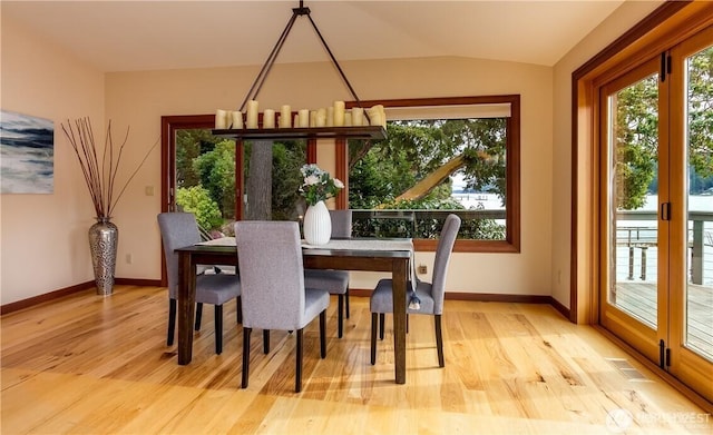 dining area featuring light wood-style floors, a healthy amount of sunlight, and vaulted ceiling