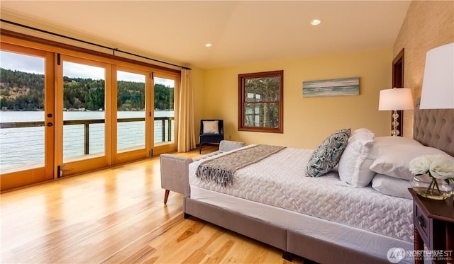 bedroom featuring access to outside, recessed lighting, a water view, and light wood-style floors