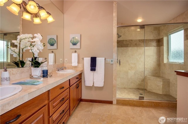 full bathroom featuring tiled shower, a sink, baseboards, and double vanity