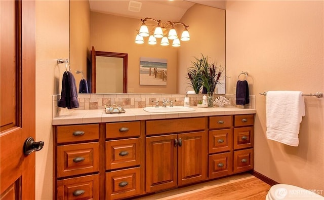 bathroom featuring tasteful backsplash, visible vents, vanity, and wood finished floors