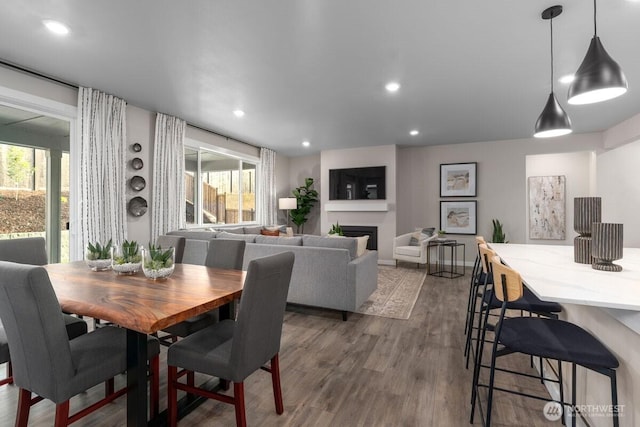 dining room featuring dark wood-type flooring, plenty of natural light, a fireplace, and recessed lighting