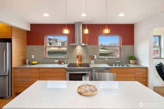 kitchen featuring modern cabinets, appliances with stainless steel finishes, brown cabinets, wall chimney range hood, and a sink