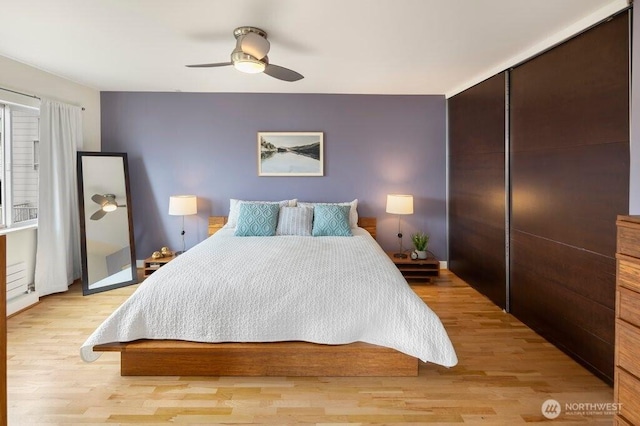 bedroom with ceiling fan, light wood finished floors, and a closet