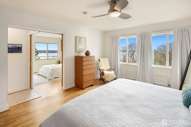 bedroom with light wood finished floors, a ceiling fan, and baseboards