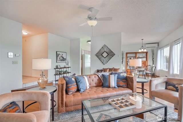 living room with a textured ceiling, an AC wall unit, wood finished floors, and a ceiling fan