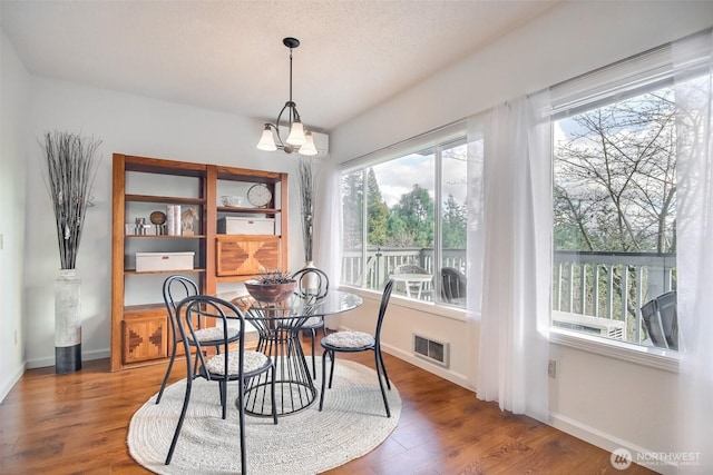 dining room with visible vents, wood finished floors, baseboards, and a chandelier