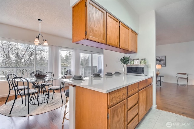 kitchen featuring stainless steel microwave, light wood-style flooring, light countertops, and a textured ceiling