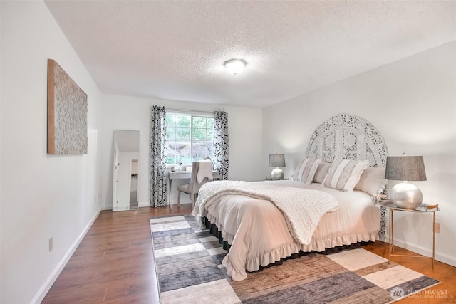 bedroom featuring wood finished floors, baseboards, and a textured ceiling