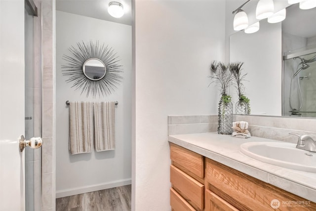 bathroom featuring a stall shower, vanity, baseboards, and wood finished floors