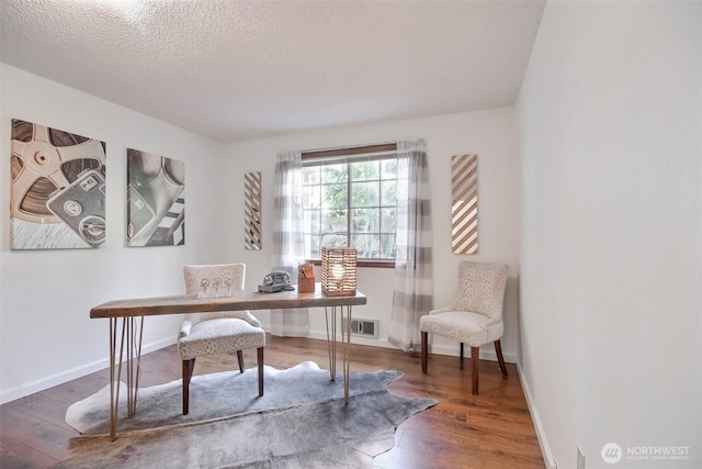 office space featuring baseboards, visible vents, wood-type flooring, and a textured ceiling