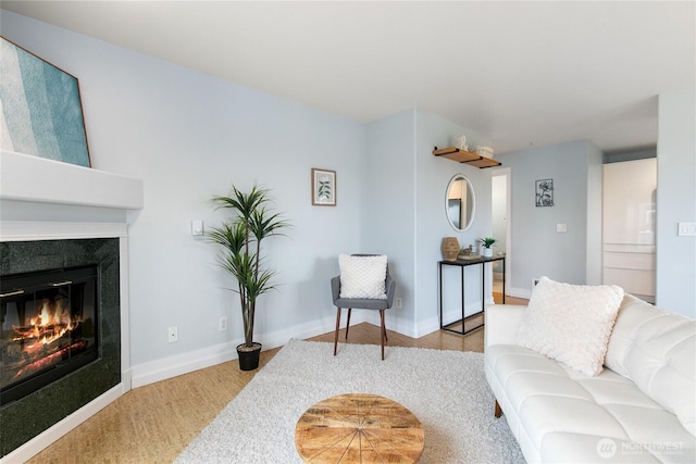 living area featuring a glass covered fireplace, baseboards, and wood finished floors