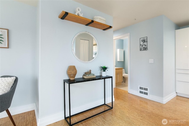 hallway featuring visible vents and baseboards