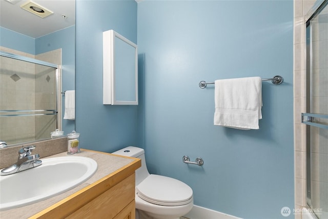 bathroom featuring toilet, vanity, and a tile shower