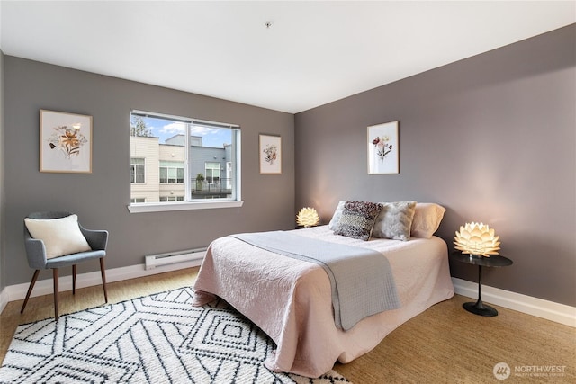 bedroom with baseboard heating, baseboards, and wood finished floors