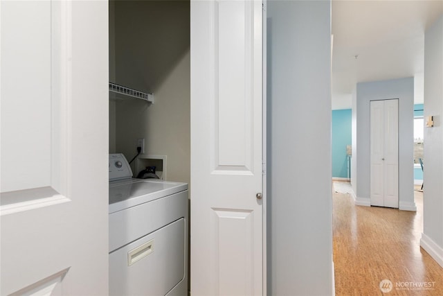 clothes washing area featuring laundry area, washer / dryer, light wood-style flooring, and baseboards