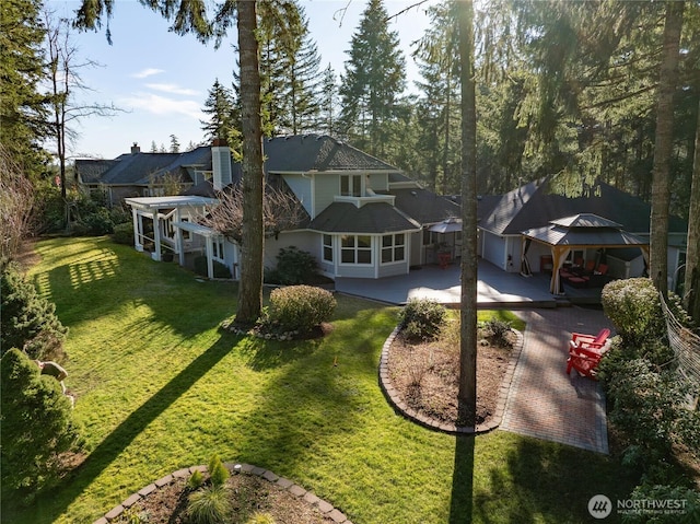 back of property featuring a patio area, a lawn, driveway, and a gazebo